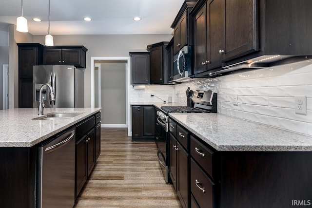 12475 Speranza Dr, Fort Wayne, IN 46818 - kitchen featuring appliances with stainless steel finishes, a sink, wood finished floors, decorative backsplash, and light stone countertops