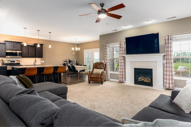 12475 Speranza Dr, Fort Wayne, IN 46818 - living area with a chandelier, a tiled fireplace, a ceiling fan, and light carpet