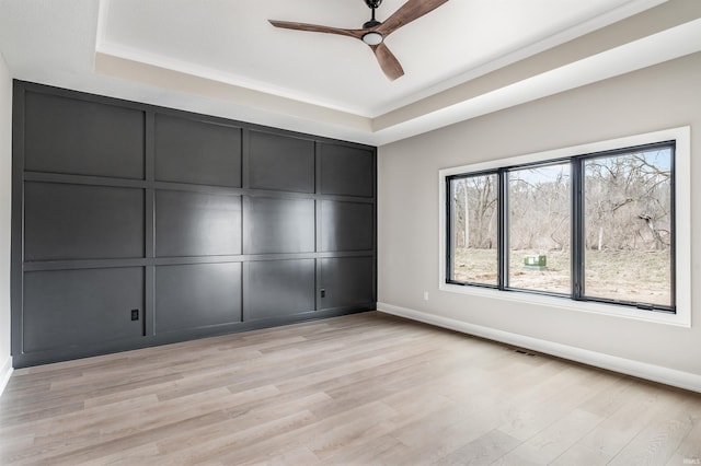 12318 Rain Lily Ct, Fort Wayne, IN 46814 - unfurnished bedroom with a raised ceiling, baseboards, a decorative wall, light wood finished floors, and ceiling fan
