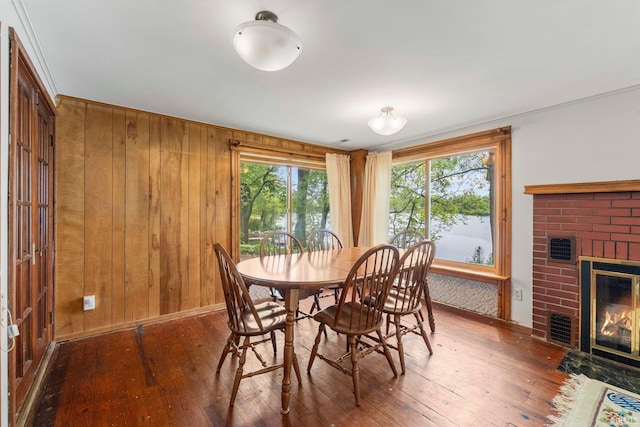 9465 E 1000 N, Syracuse, IN 46567 - dining area featuring hardwood / wood-style floors, a brick fireplace, wooden walls, and baseboards