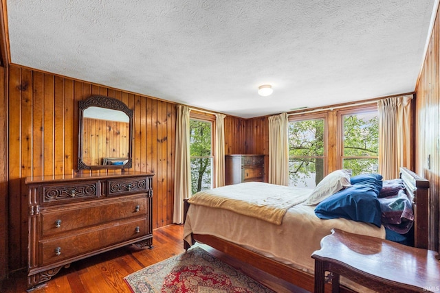 9465 E 1000 N, Syracuse, IN 46567 - bedroom featuring multiple windows, a textured ceiling, dark wood-style flooring, and wood walls