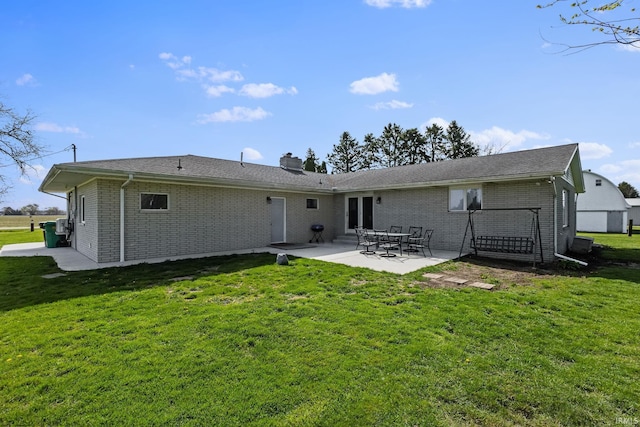 56915 Tulip Rd, New Carlisle, IN 46552 - rear view of property featuring brick siding, a patio area, a lawn, and a chimney