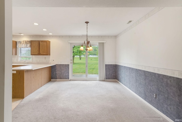 3260 E Sherman St, Columbia City, IN 46725 - kitchen featuring brown cabinetry, light carpet, wallpapered walls, decorative light fixtures, and a chandelier