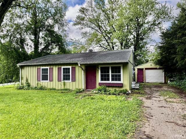 207 S Poplar Dr, Bloomington, IN 47429 - view of front of home with asphalt driveway, an outdoor structure, board and batten siding, a front yard, and a detached garage