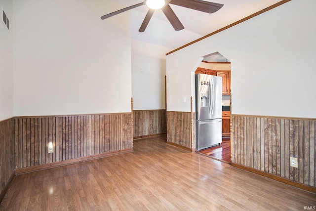 724 E Mishawaka Ave, Mishawaka, IN 46545 - empty room featuring a wainscoted wall, ceiling fan, light wood-style flooring, wooden walls, and arched walkways