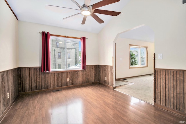 724 E Mishawaka Ave, Mishawaka, IN 46545 - empty room with a wainscoted wall, wood finished floors, arched walkways, wooden walls, and ceiling fan