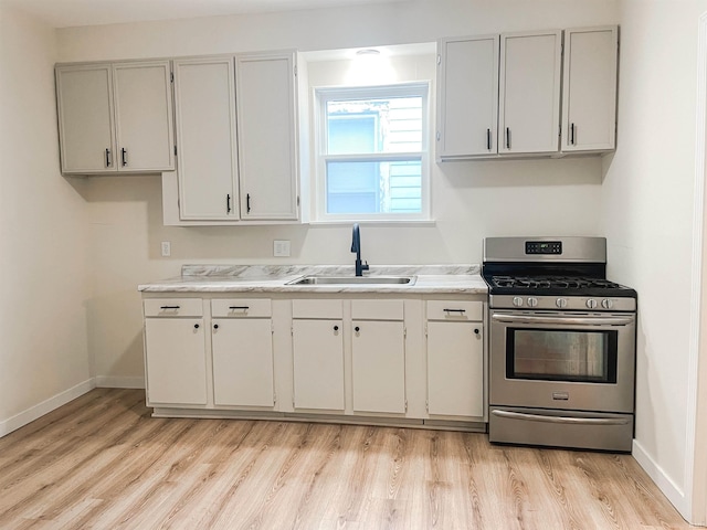 511 E 3rd St, Peru, IN 46970 - kitchen featuring gas range, a sink, light wood-style flooring, light countertops, and baseboards