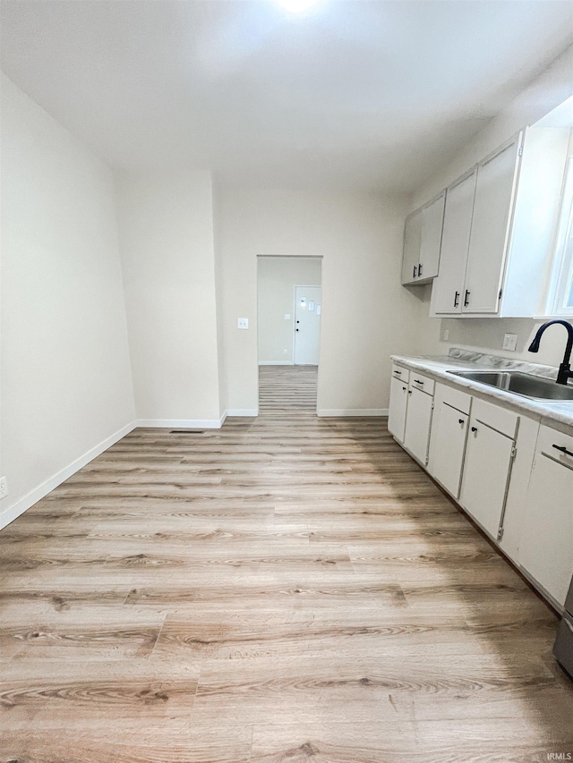 511 E 3rd St, Peru, IN 46970 - kitchen with light wood-style floors, baseboards, a sink, and white cabinets