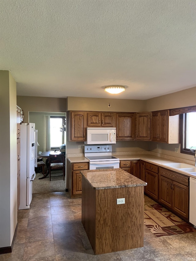 6921 Franke Rd, Fort Wayne, IN 46816 - kitchen with white appliances, a sink, a kitchen island, a textured ceiling, and brown cabinetry