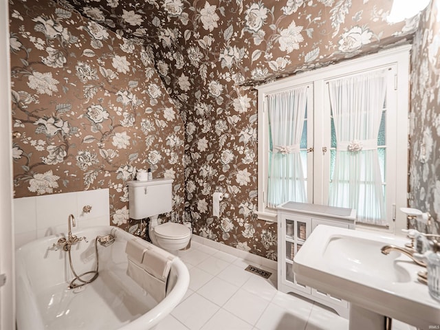 703 Pfeiffer Rd, Evansville, IN 47711 - bathroom with tile patterned floors, toilet, a tub to relax in, baseboards, and wallpapered walls