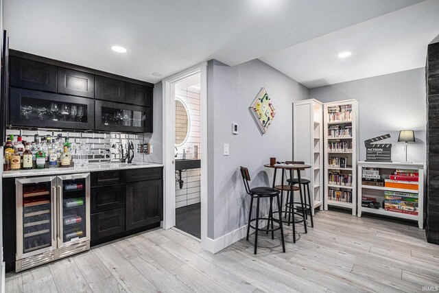 53760 Terre Verde Hills Ct, South Bend, IN 46628 - indoor wet bar featuring wine cooler, light wood finished floors, baseboards, decorative backsplash, and recessed lighting