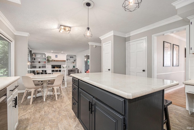 51695 Fox Pointe Ln, Granger, IN 46530 - kitchen with a lit fireplace, light countertops, stainless steel dishwasher, ornamental molding, and pendant lighting