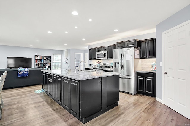 7228 W Mustang Dr, Ellettsville, IN 47429 - kitchen with stainless steel appliances, dark cabinetry, a center island with sink, backsplash, and recessed lighting