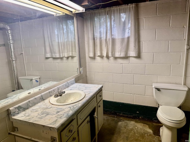 815 3rd St, Huntingburg, IN 47542 - bathroom featuring toilet, concrete block wall, vanity, and unfinished concrete flooring