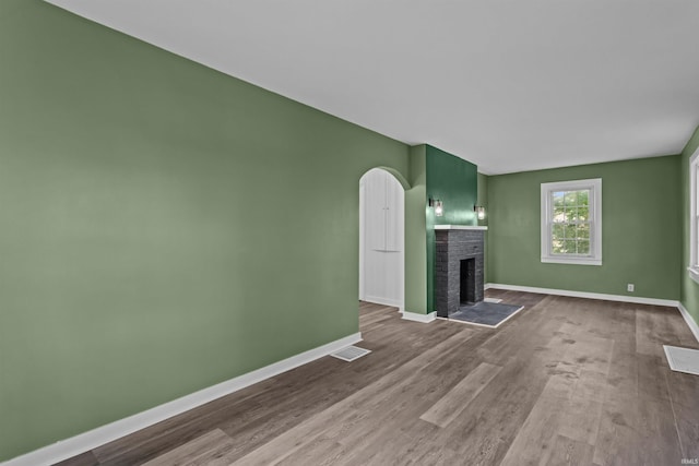 112 W Monroe St, Alexandria, IN 46001 - unfurnished living room featuring a fireplace, baseboards, wood finished floors, and arched walkways