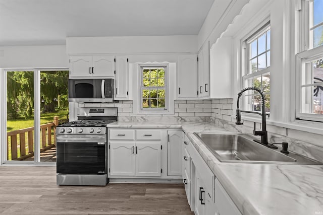 112 W Monroe St, Alexandria, IN 46001 - kitchen with appliances with stainless steel finishes, a sink, white cabinetry, and backsplash