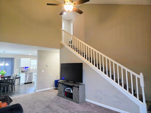 405 Ariel Dr, Kokomo, IN 46901 - carpeted living area with stairs, ceiling fan, a chandelier, baseboards, and a towering ceiling