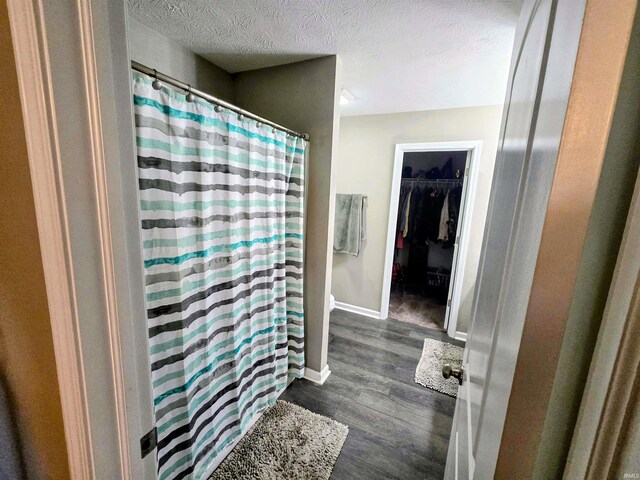 405 Ariel Dr, Kokomo, IN 46901 - full bath with wood finished floors, a shower with shower curtain, a walk in closet, a textured ceiling, and baseboards