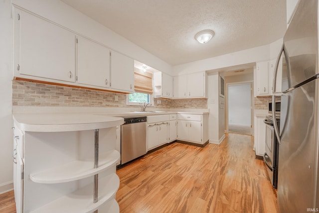 2305 S Dixon Rd, Kokomo, IN 46902 - kitchen with appliances with stainless steel finishes, light countertops, white cabinetry, light wood finished floors, and decorative backsplash