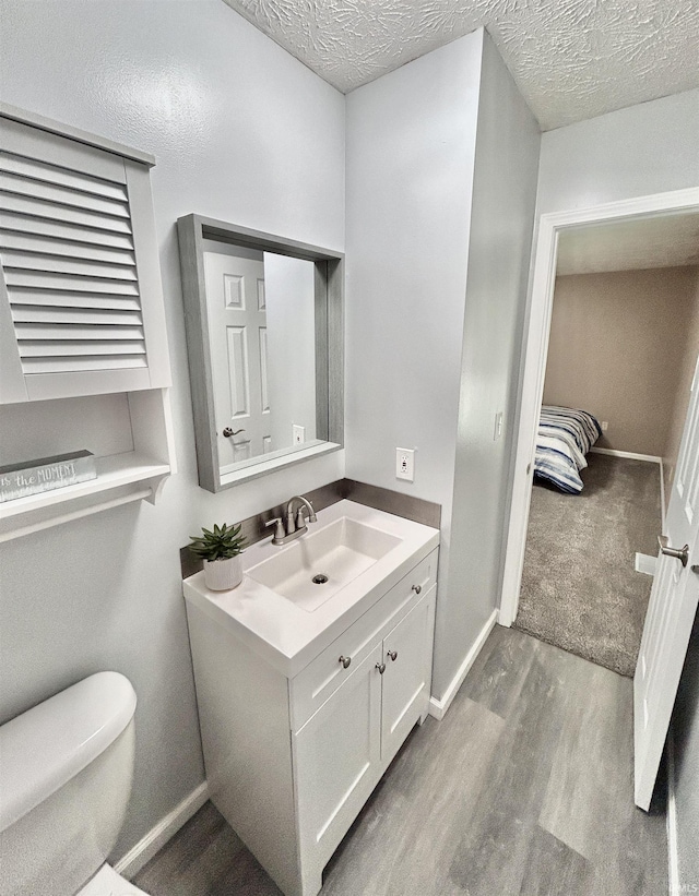 305 N Maude Dr, Rossville, IN 46065 - half bath with vanity, wood finished floors, toilet, baseboards, and a textured ceiling