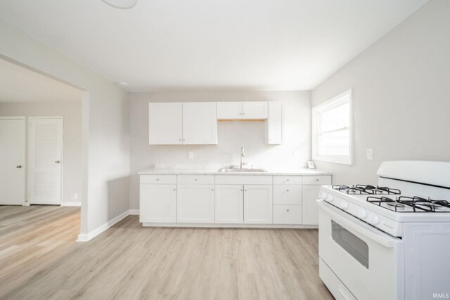 2726 Apache Dr, Anderson, IN 46012 - kitchen with gas range gas stove, a sink, light wood finished floors, and white cabinetry