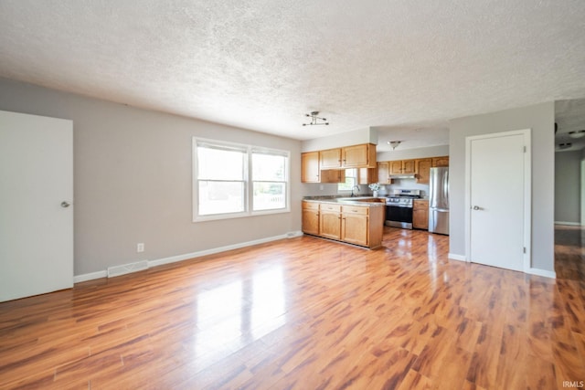 6863 W Jennifer Ct, Greenfield, IN 46140 - kitchen with stainless steel appliances, open floor plan, a textured ceiling, light wood-style floors, and baseboards
