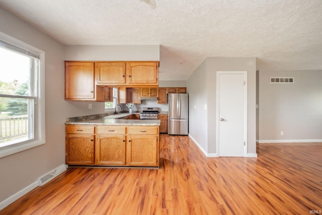 6863 W Jennifer Ct, Greenfield, IN 46140 - kitchen with stainless steel appliances, light wood-type flooring, baseboards, a peninsula, and a textured ceiling