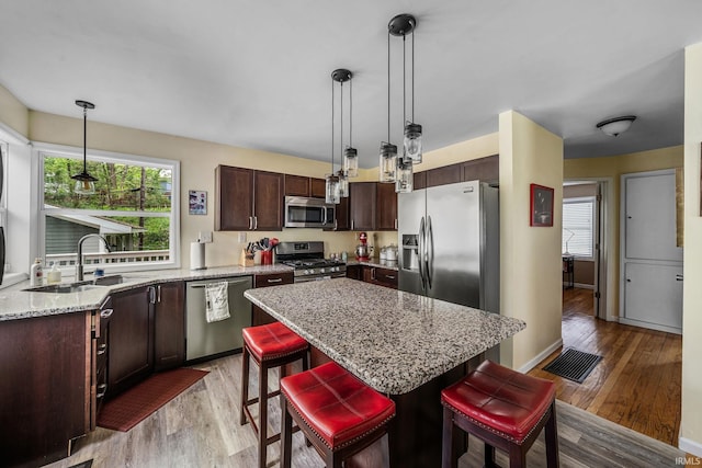 1905 Inglewood Pl, South Bend, IN 46616 - kitchen featuring appliances with stainless steel finishes, a sink, light wood-type flooring, dark brown cabinets, and a breakfast bar