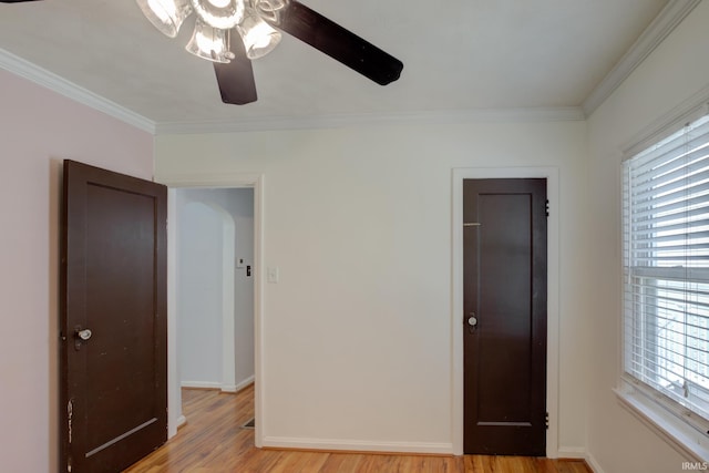 1521 Monroe Ave, Evansville, IN 47714 - unfurnished bedroom featuring light wood finished floors, ornamental molding, arched walkways, baseboards, and a ceiling fan