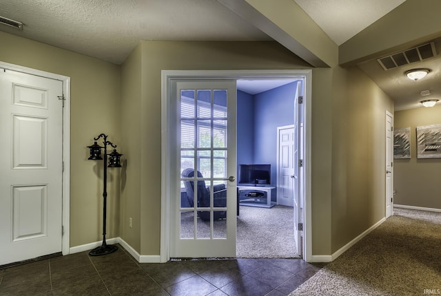 229 Ironwood Ln, Ossian, IN 46777 - foyer entrance with dark colored carpet, dark tile patterned flooring, baseboards, and a textured ceiling