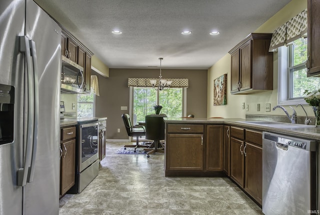 229 Ironwood Ln, Ossian, IN 46777 - kitchen with appliances with stainless steel finishes, a sink, a chandelier, a textured ceiling, and a peninsula