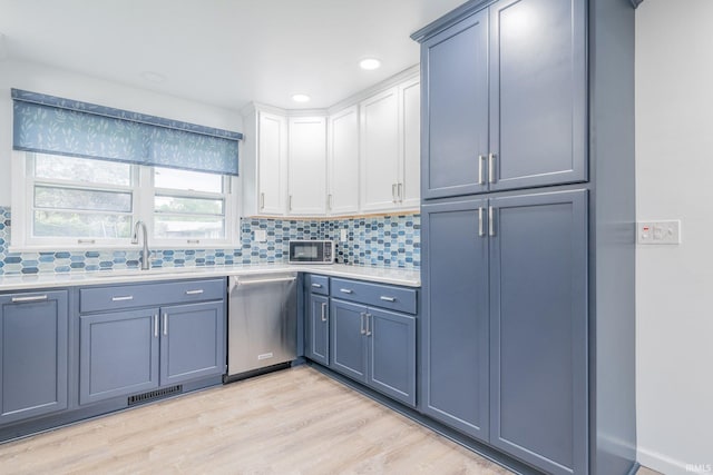 902 Hawthorne Ln, Logansport, IN 46947 - kitchen with dishwasher, a sink, light countertops, light wood-style floors, and decorative backsplash