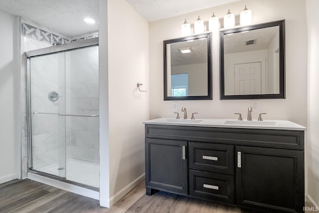 355 Blinn Ave, Frankfort, IN 46041 - bathroom featuring wood finished floors, baseboards, double vanity, a shower stall, and a textured ceiling