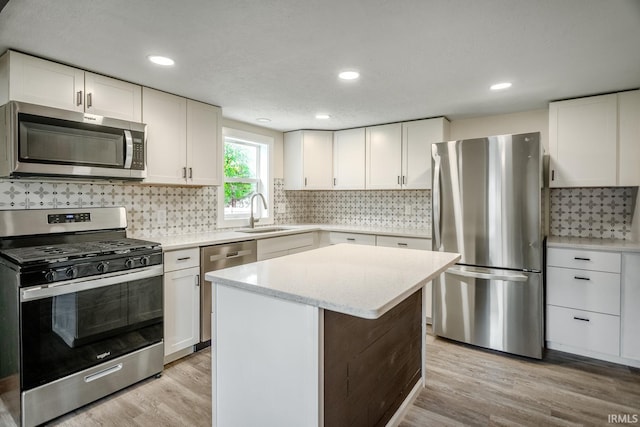 355 Blinn Ave, Frankfort, IN 46041 - kitchen featuring appliances with stainless steel finishes, a sink, light wood-type flooring, decorative backsplash, and white cabinetry