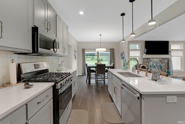 15332 Annabelle Pl, Leo, IN 46765 - kitchen with appliances with stainless steel finishes, a sink, wood finished floors, tasteful backsplash, and healthy amount of natural light
