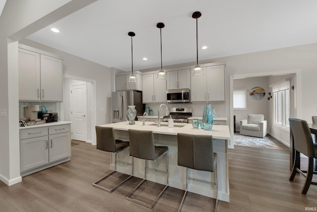 15332 Annabelle Pl, Leo, IN 46765 - kitchen featuring stainless steel appliances, a sink, a breakfast bar area, light wood-type flooring, and light countertops