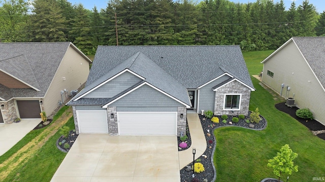 15332 Annabelle Pl, Leo, IN 46765 - view of front of home with stone siding, concrete driveway, an attached garage, roof with shingles, and a front lawn