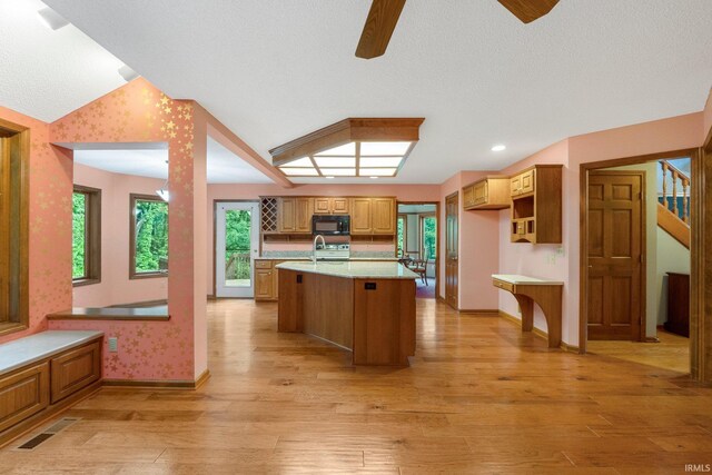2711 Spring Creek Dr, Fort Wayne, IN 46808 - kitchen featuring black microwave, vaulted ceiling, light countertops, light wood-type flooring, and ceiling fan