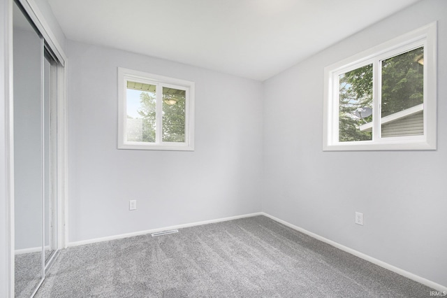 4113 York Rd, South Bend, IN 46614 - unfurnished bedroom featuring multiple windows, carpet floors, a closet, and baseboards
