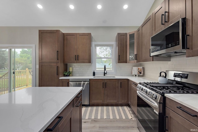 51650 Prescott Ave, South Bend, IN 46637 - kitchen featuring appliances with stainless steel finishes, a sink, light wood-style flooring, light stone counters, and decorative backsplash