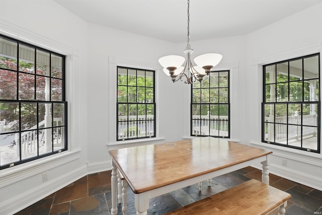 dining area featuring stone tile flooring, a chandelier, and baseboards