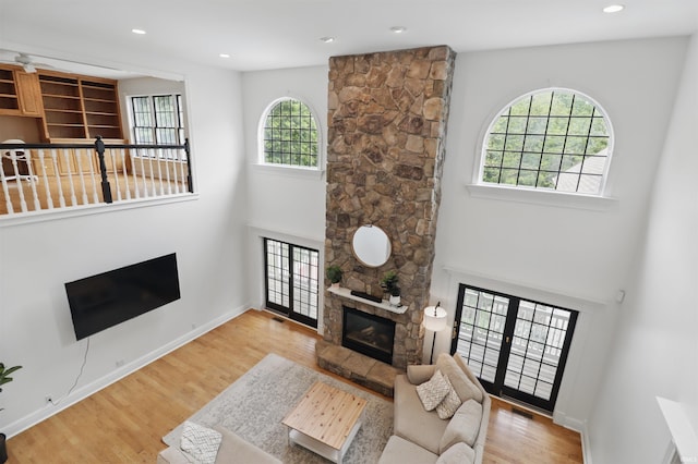 living room featuring a fireplace, wood finished floors, a high ceiling, recessed lighting, and baseboards