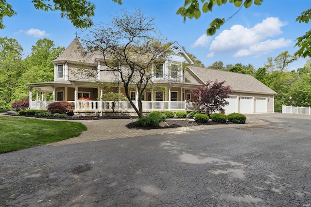 victorian house with a porch, asphalt driveway, and an attached garage