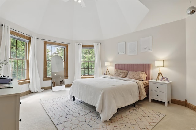 bedroom featuring light colored carpet, baseboards, and high vaulted ceiling