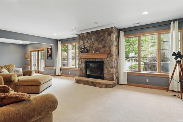 carpeted living room with baseboards, a stone fireplace, and recessed lighting