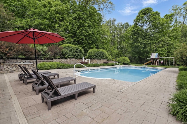swimming pool featuring a patio area and a playground