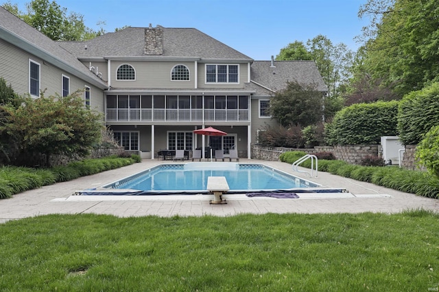 view of pool with a sunroom, a patio, and a lawn
