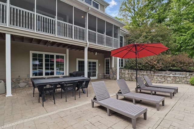 view of patio featuring outdoor dining area and a sunroom