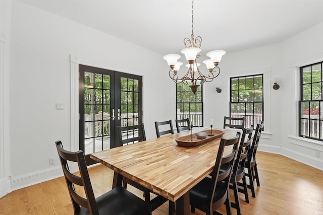 dining room with light wood finished floors, a chandelier, french doors, and baseboards