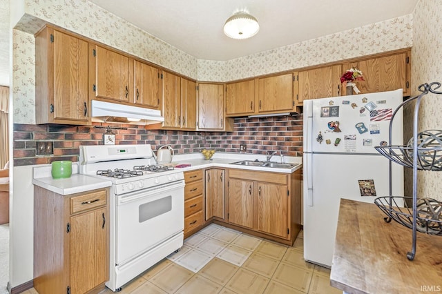 5023 Cedarwood Ln, South Bend, IN 46619 - kitchen featuring white appliances, under cabinet range hood, wallpapered walls, a sink, and light countertops